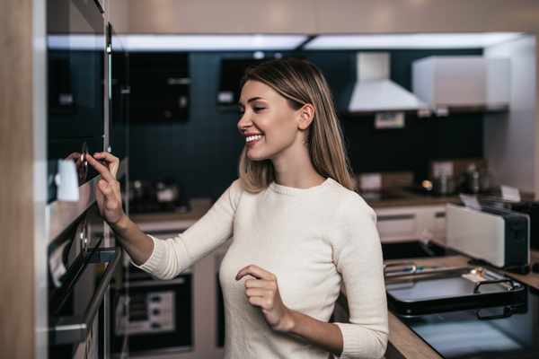 A smiling woman trying out an oven in a store